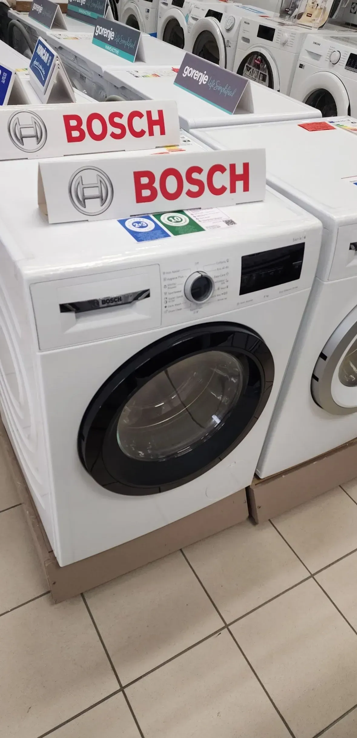 Bosch front-load washing machines displayed in an appliance store aisle.