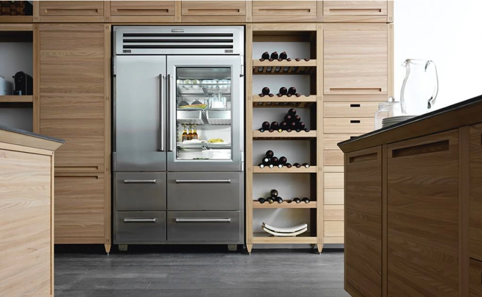 Stainless steel refrigerator with freezer drawers in a modern kitchen with wood cabinetry