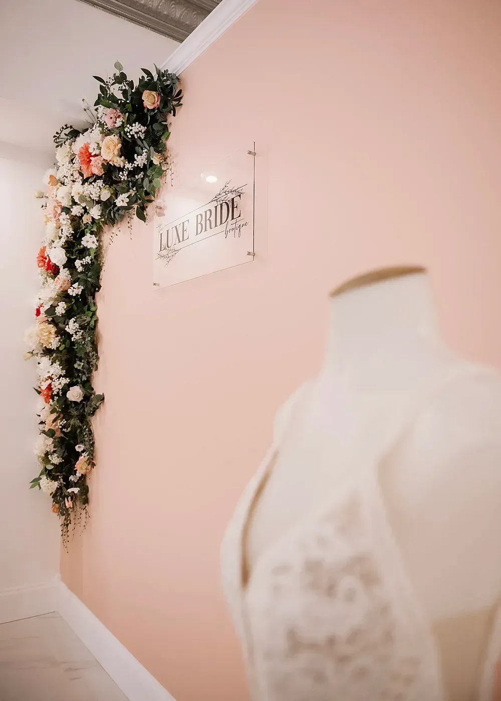 Pink wall with floral garland and sign for 