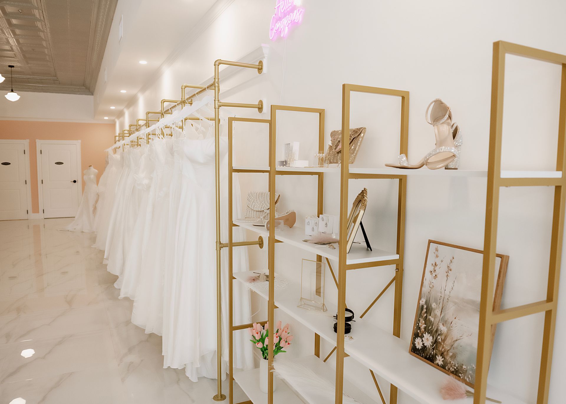 Wedding dress shop interior with dresses on a rack and display shelves with decor.