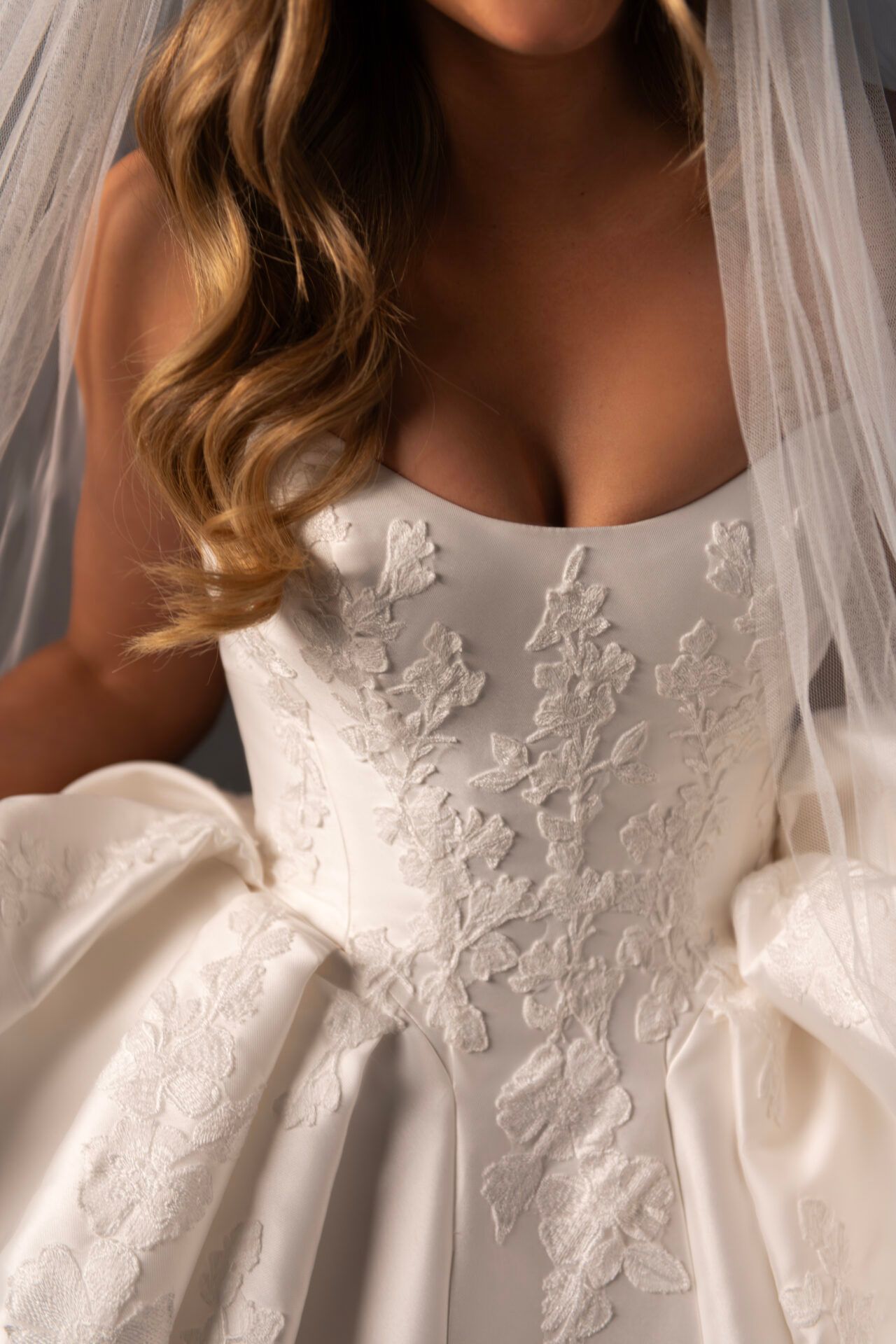Bride in strapless white wedding dress with lace bodice, and voluminous skirt. Veiled.
