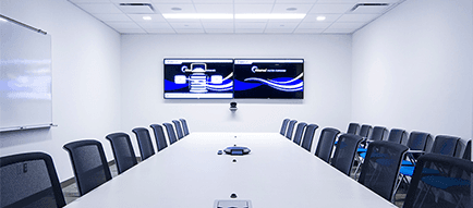 A conference room with a long table and chairs and two screens on the wall.