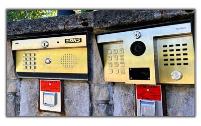 Two gold-toned residential intercom and keypad systems mounted on a stone wall, each featuring a fire department access box.