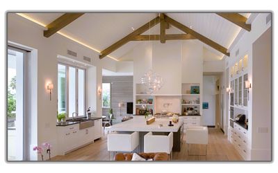 A bright, modern kitchen with white cabinets, a large central island, and exposed wood ceiling beams.