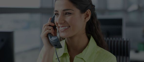 A woman is smiling while talking on a cell phone.