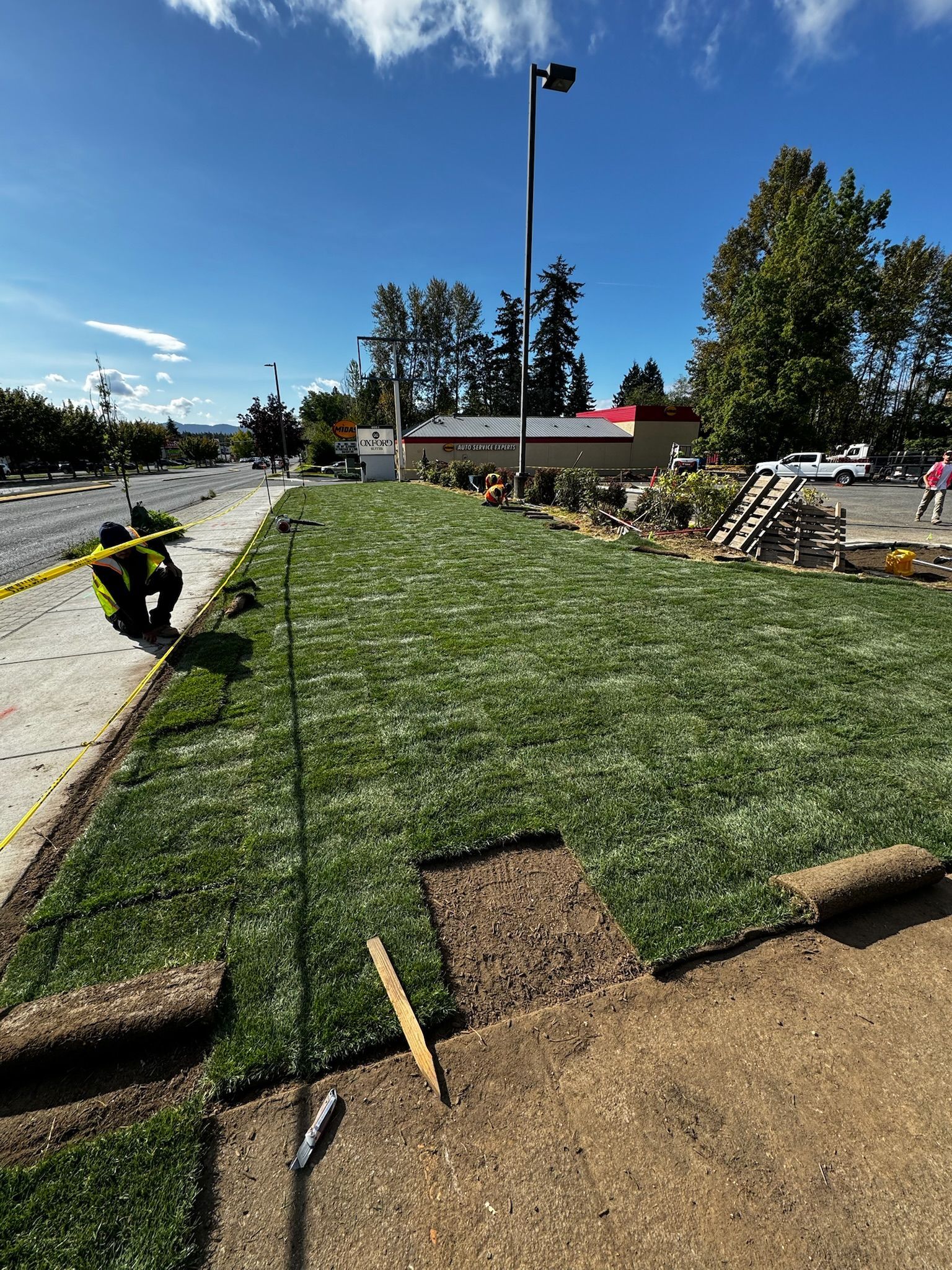 A man is working on a lawn next to a road.