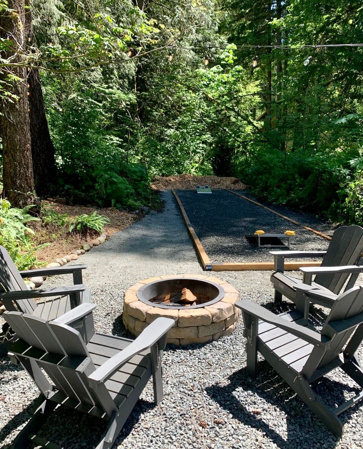 Two chairs are sitting next to a fire pit in the woods.