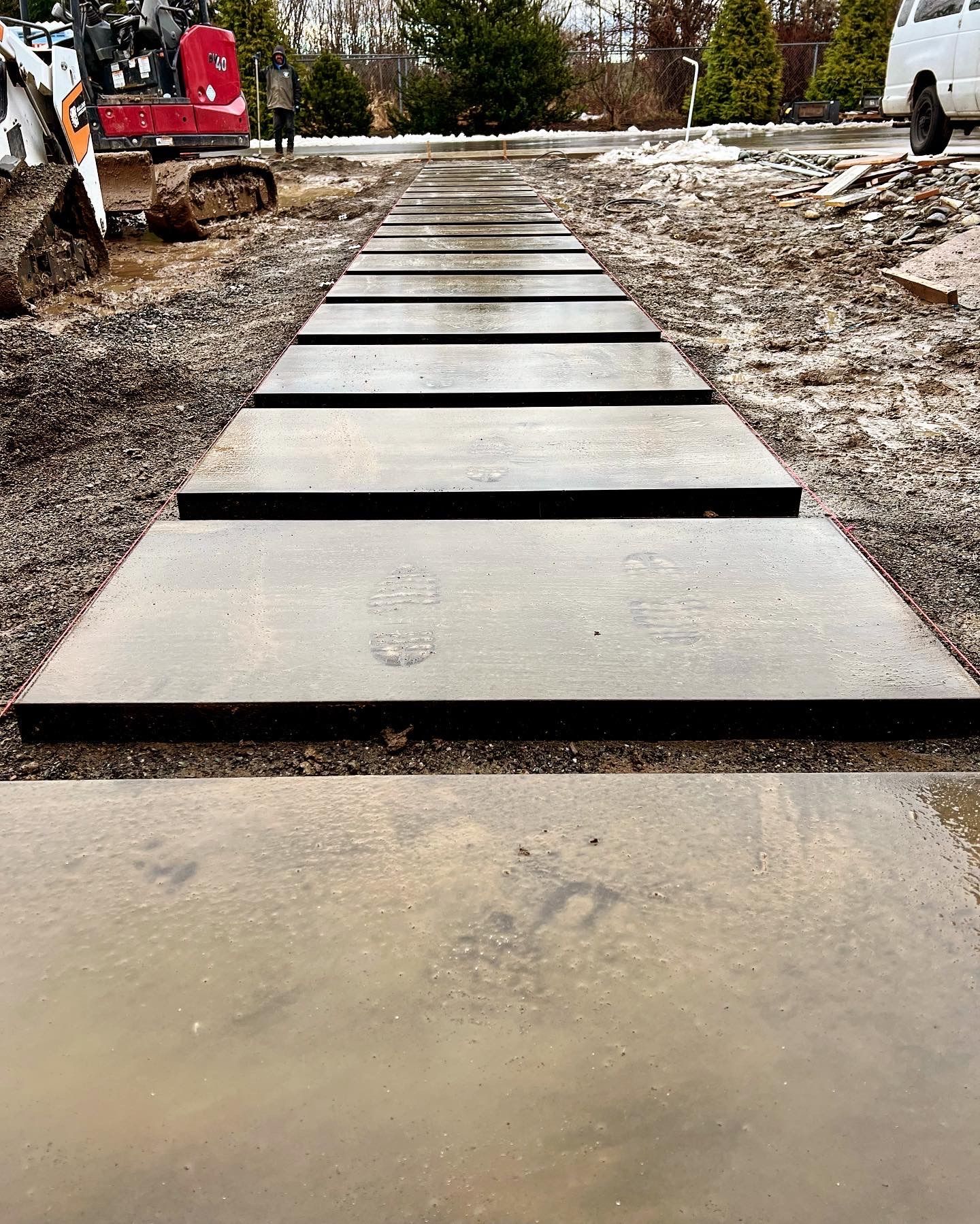 A concrete walkway is being built on a dirt road.