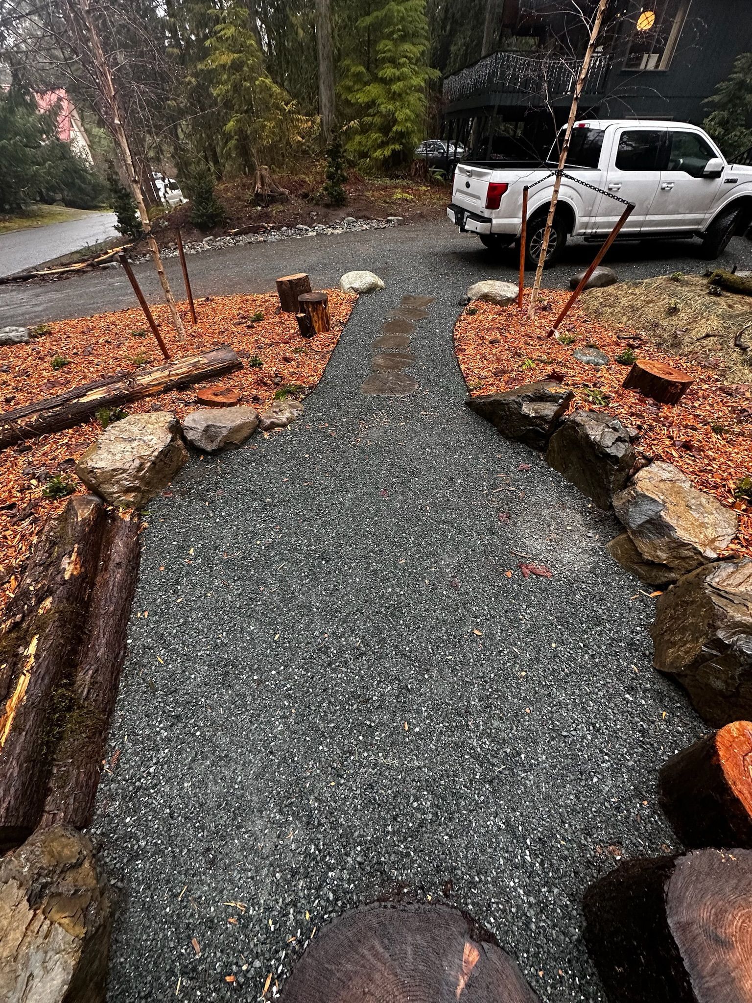 A white truck is parked in a driveway next to a stream.