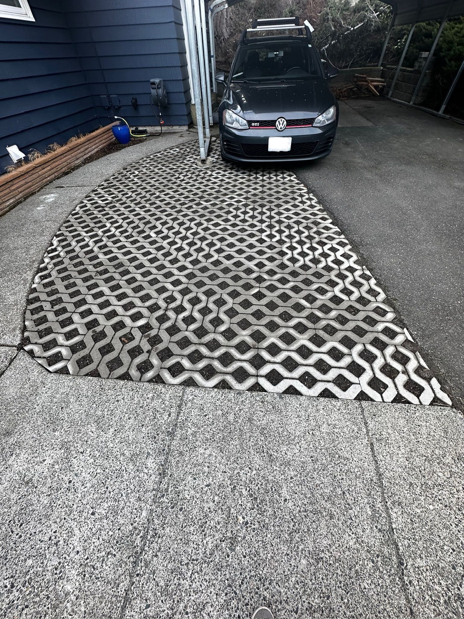 A car is parked in a driveway next to a house.
