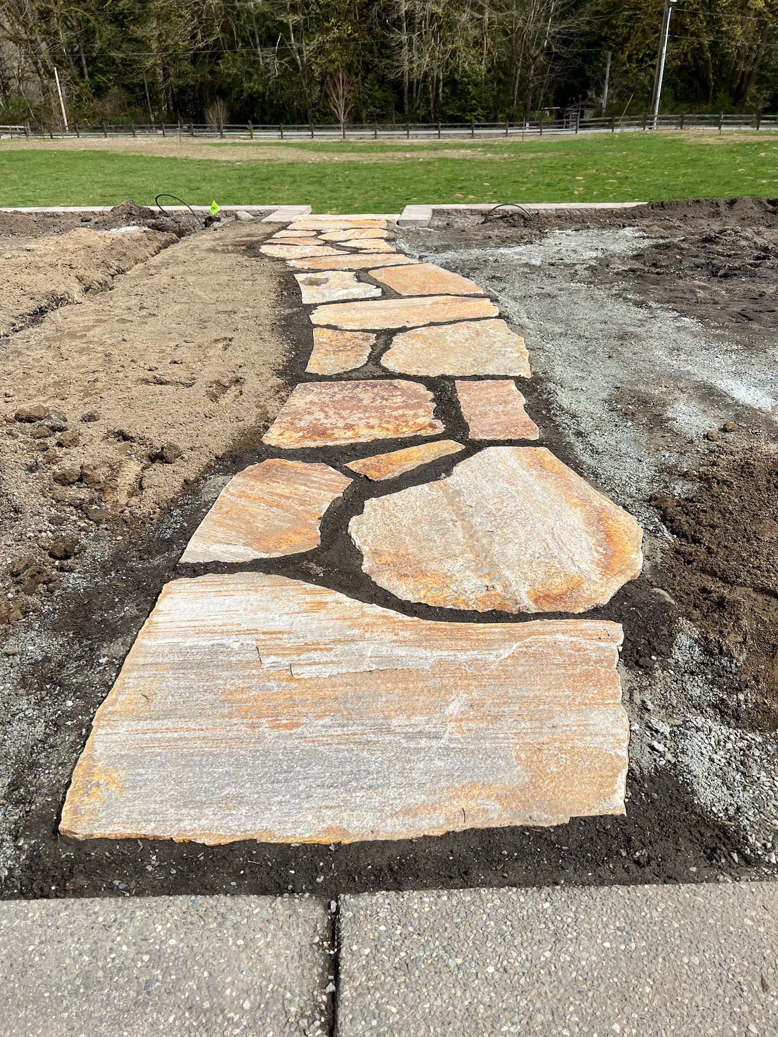 A stone walkway is being built in a yard.