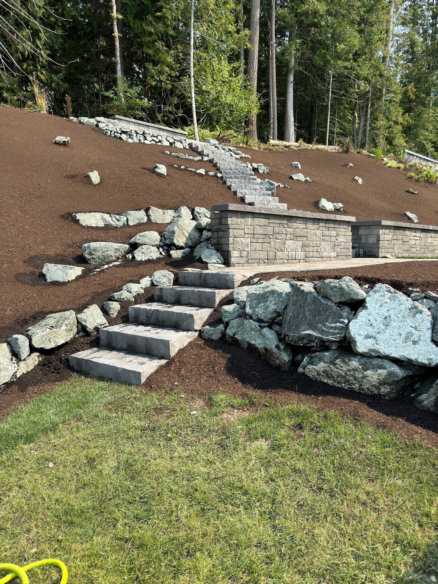 A set of stairs leading up to a rock wall in a yard.