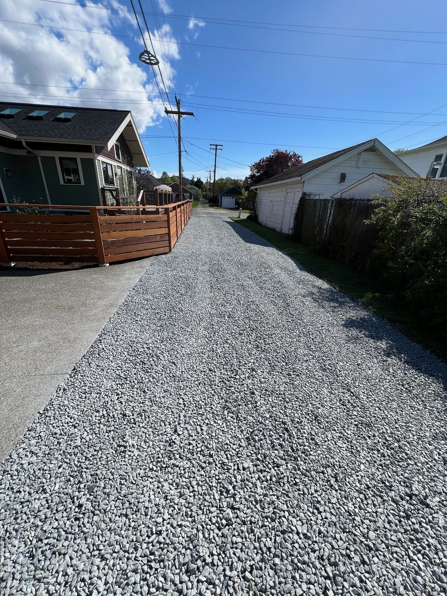 A gravel driveway leading to a house with a wooden fence.