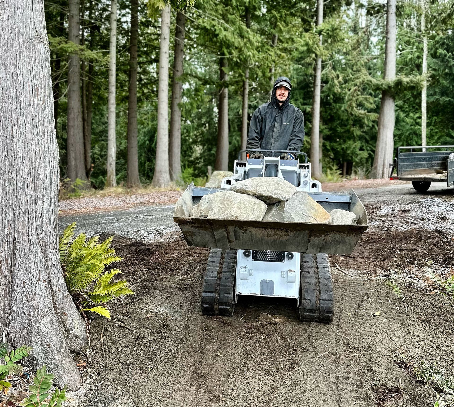 A man is driving a tractor with a bucket full of rocks.