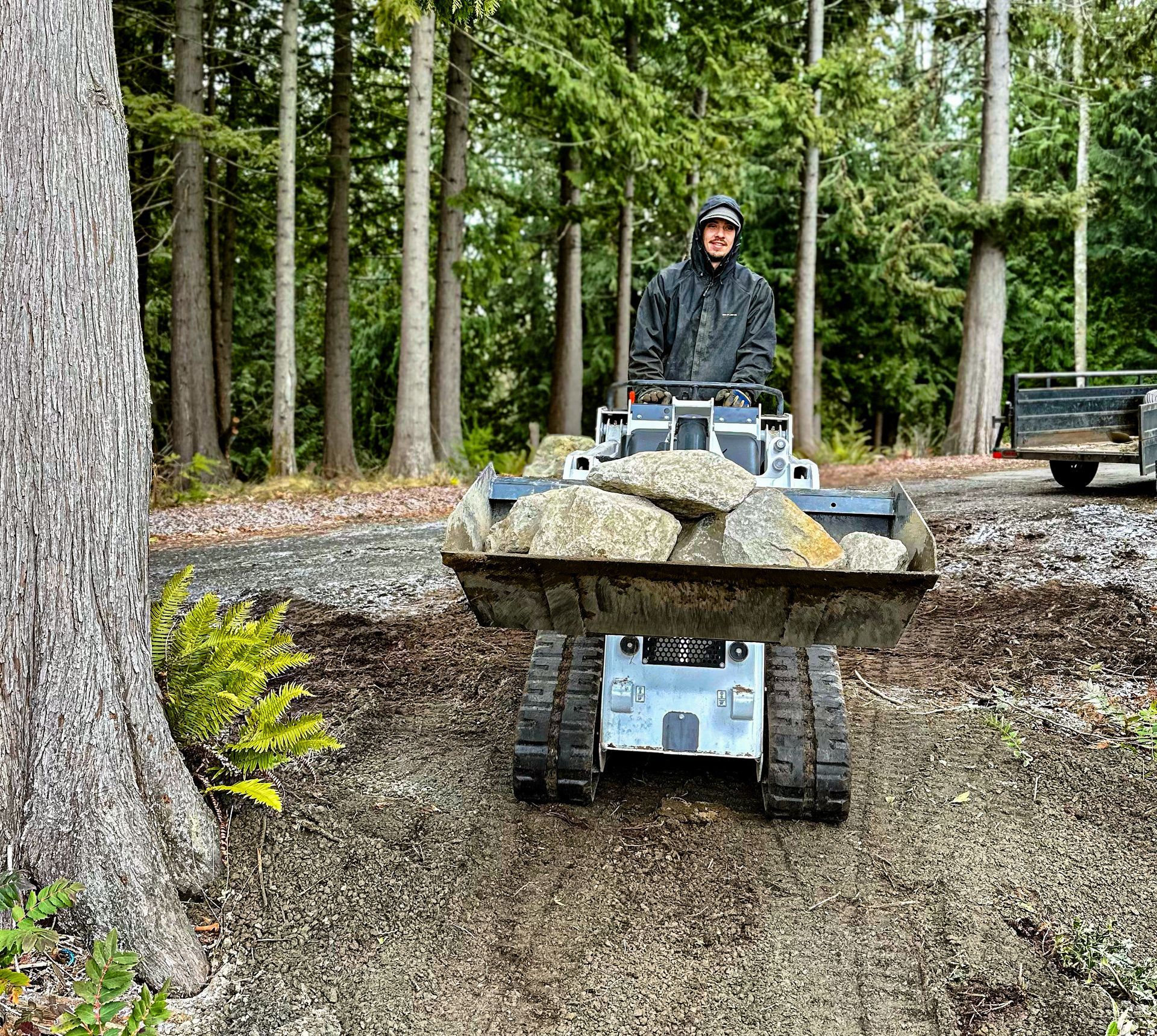 A man is driving a tractor with a bucket full of rocks.