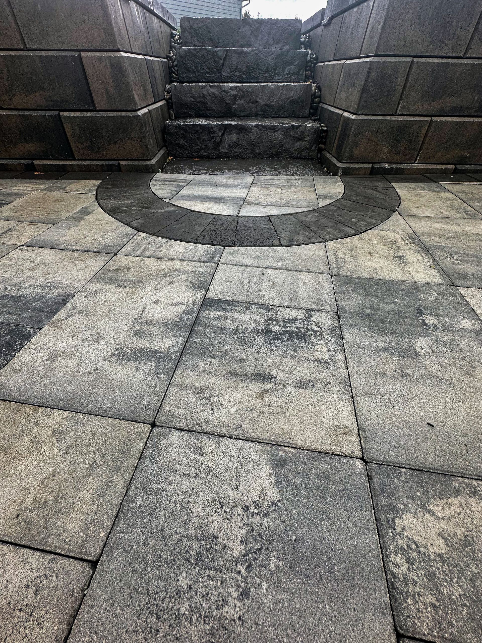 A close up of a brick walkway with stairs and a circle in the middle.