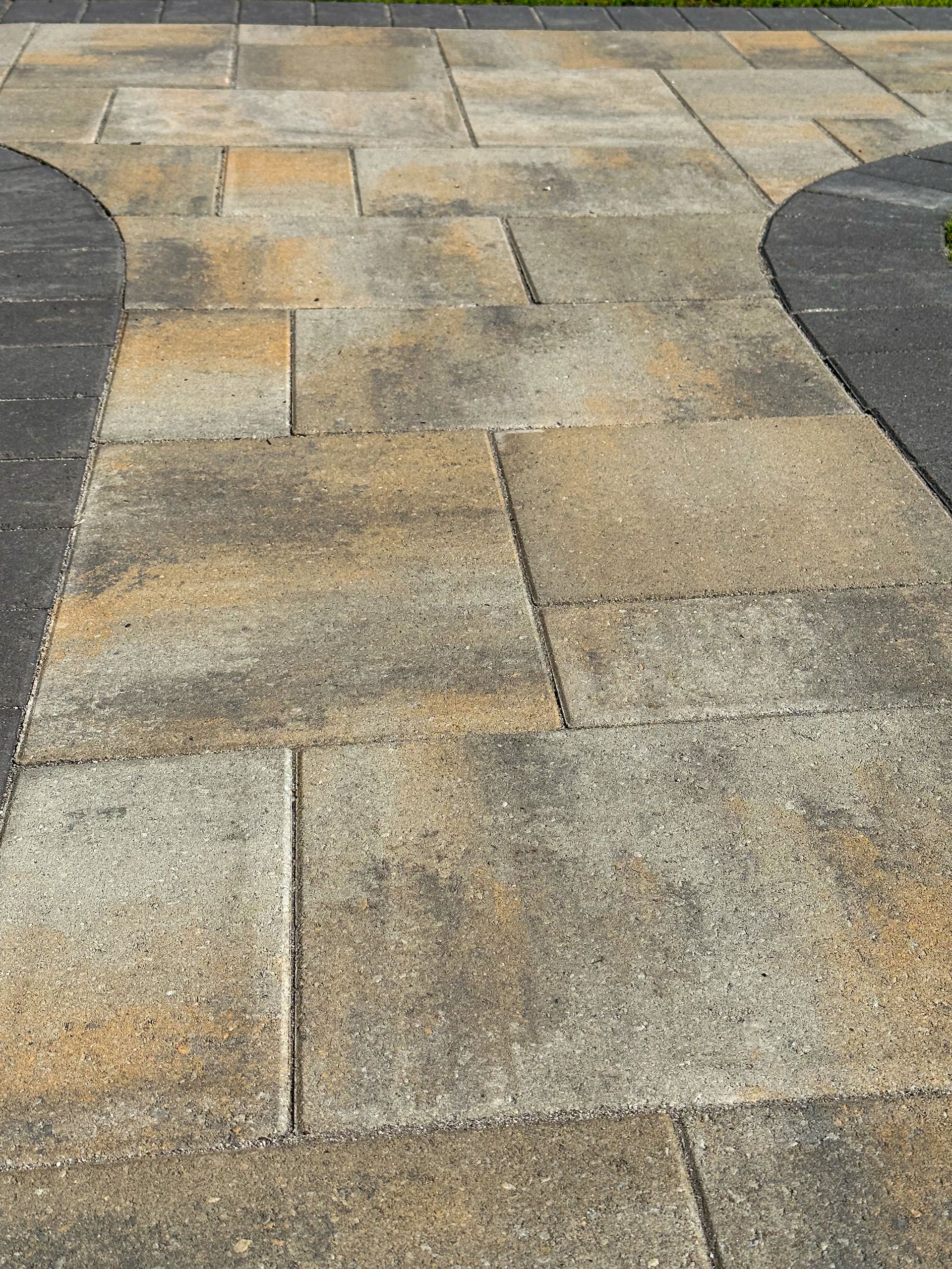 A close up of a brick walkway with a black curb.