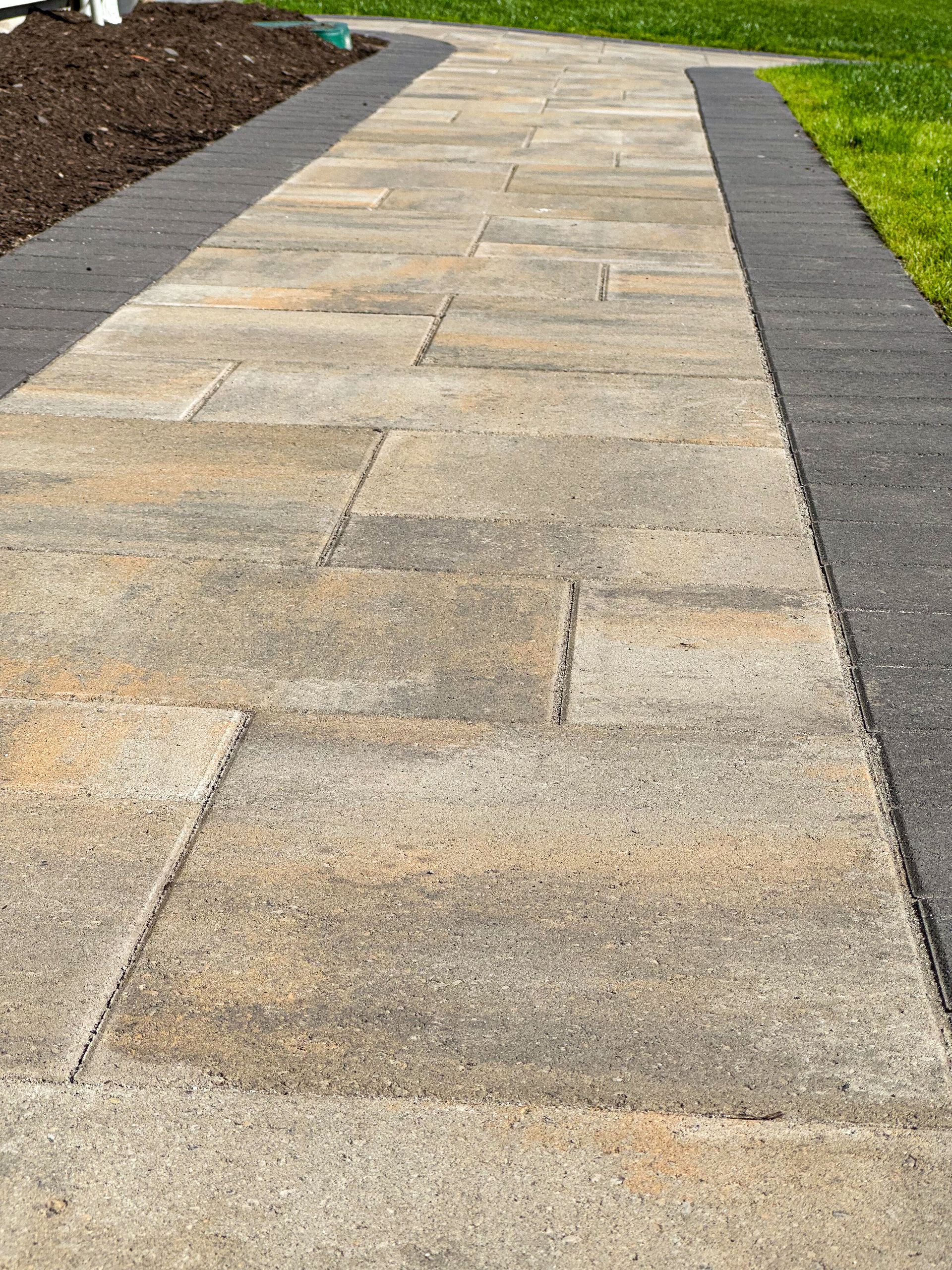 A brick walkway leading to a grassy field.