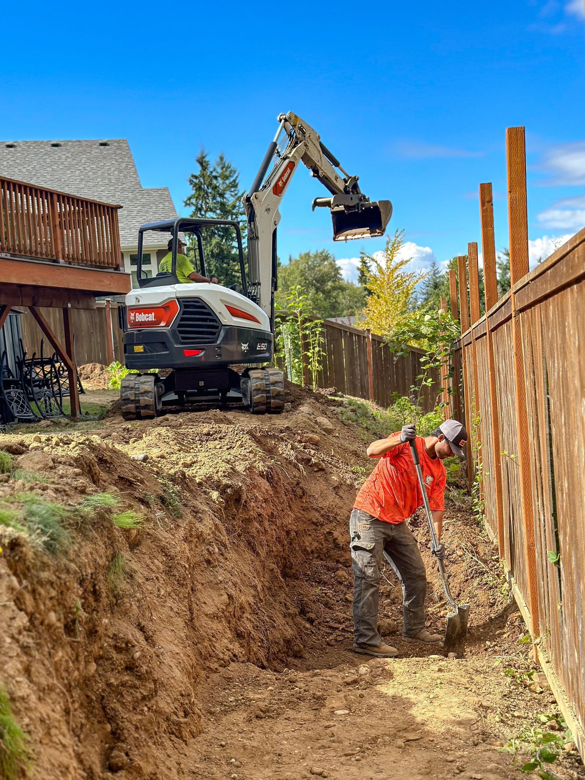 A man is digging a hole in the dirt in front of a bulldozer.