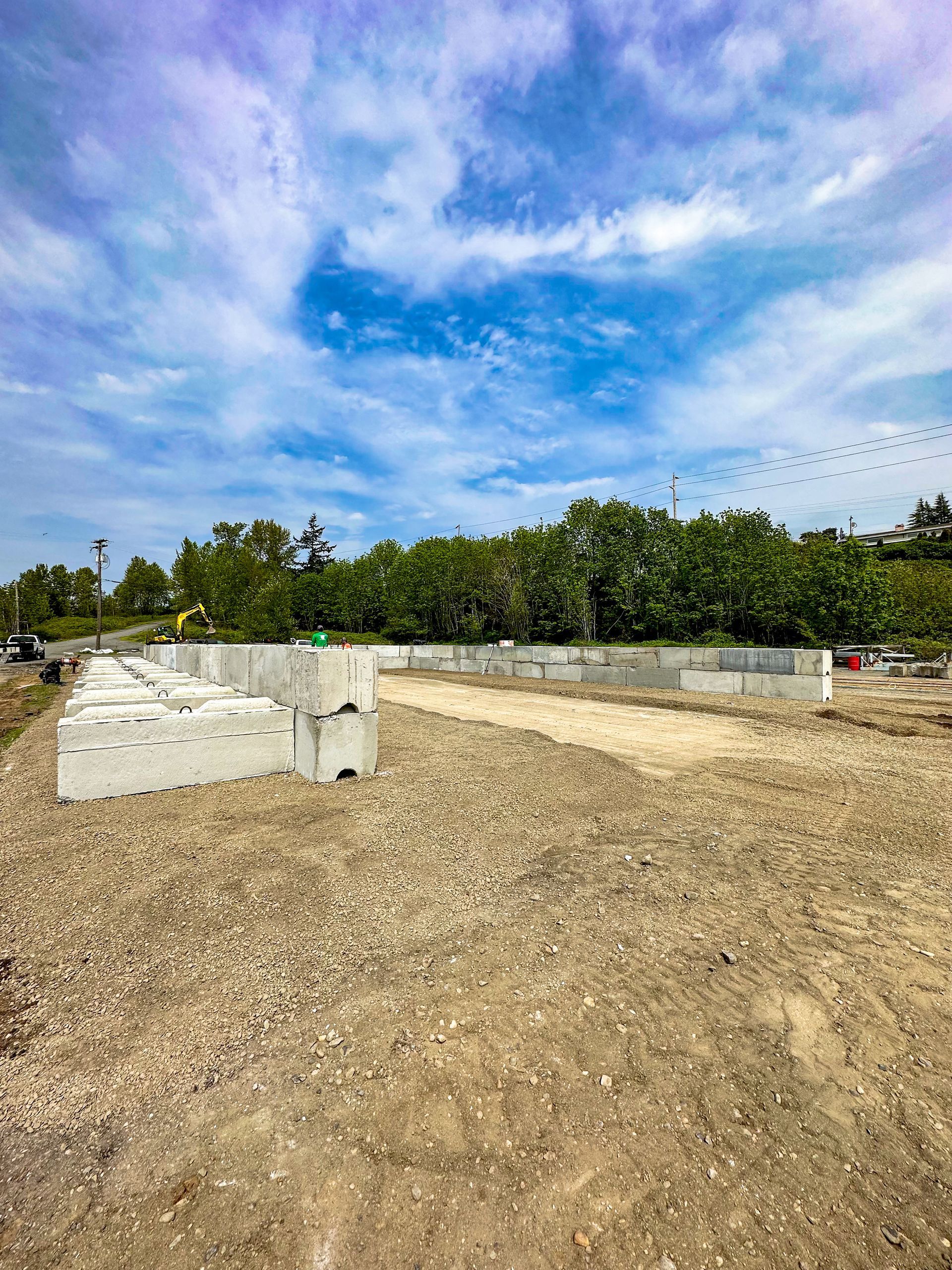 A large dirt field with a blue sky and trees in the background.