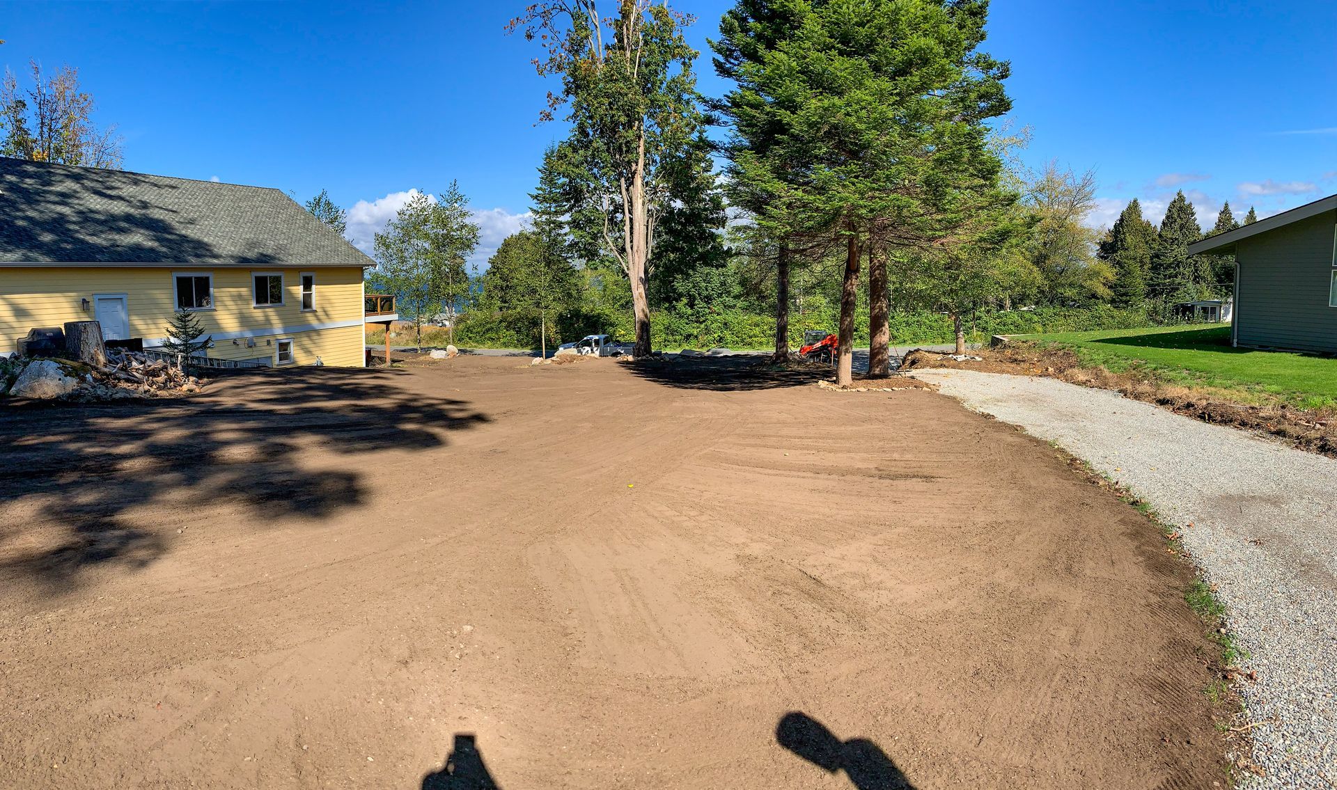 A dirt road leading to a house with trees in the background.