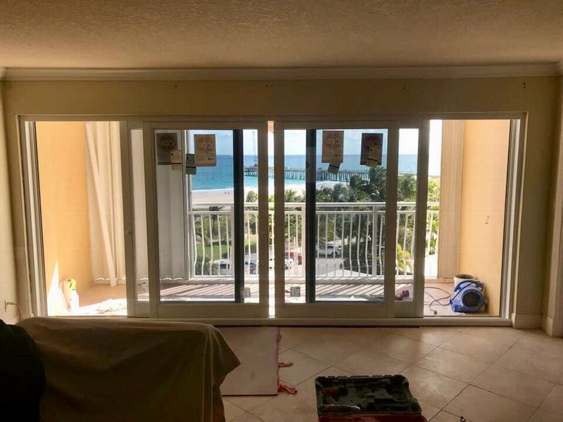 Sliding glass doors open to a balcony with an ocean view; the interior is under construction.