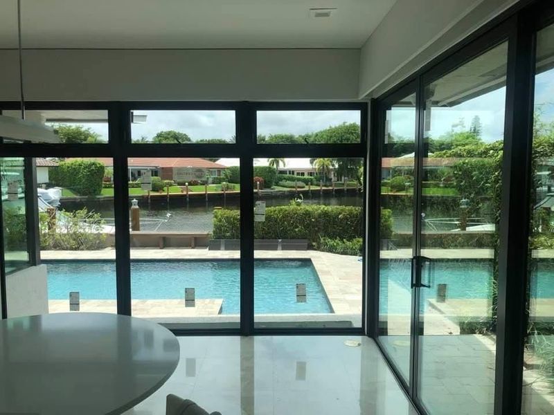 Interior view of modern home with pool and water view through large windows.