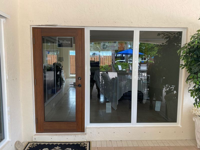 Wooden door and window with white trim, looking into a room and outdoor area with a covered table.