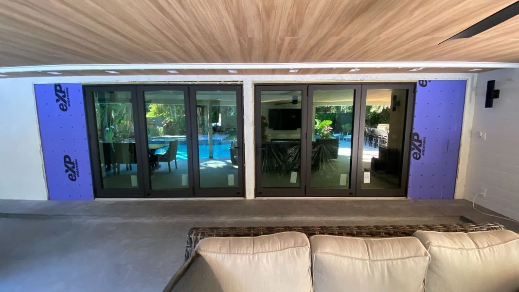 Black framed sliding glass doors with purple insulation boards, facing a pool.