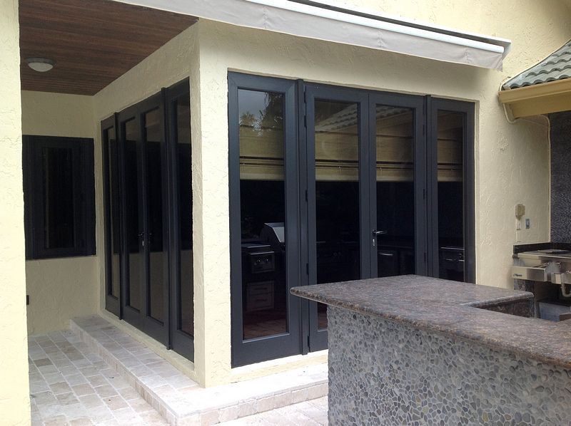 Exterior with dark-framed folding glass doors, tan walls, and a granite bar area.