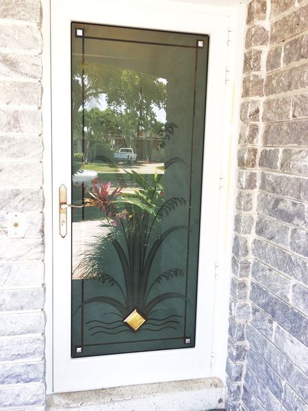 White door with decorative black metalwork and glass panel. Stone exterior.
