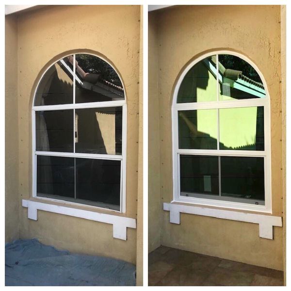 Two arched windows, before and after tinting, set in a light brown stucco wall.