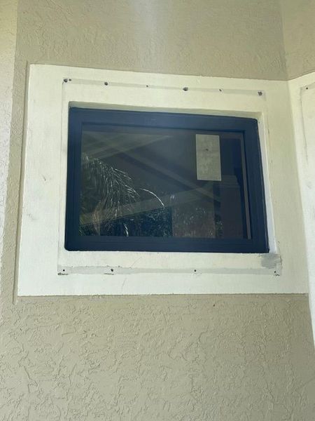 Blue framed window set in white trim on a beige stucco wall.