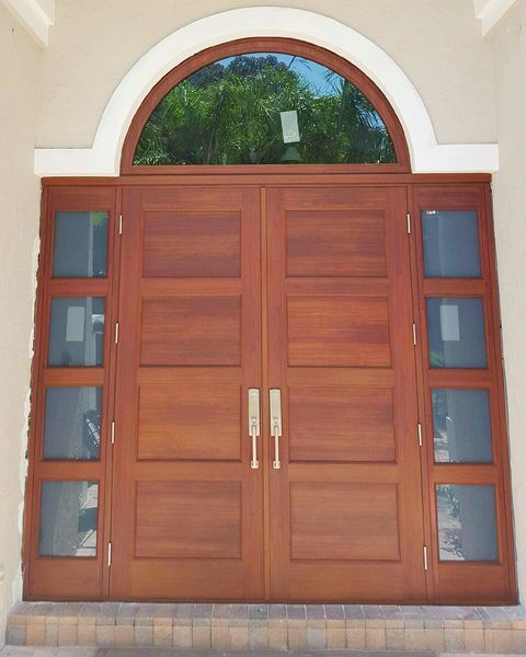Wooden double doors with sidelights and an arched window above, set in a light beige wall.