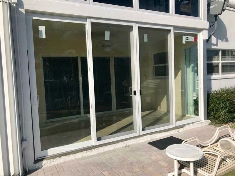 White framed sliding glass doors on a patio with outdoor furniture.