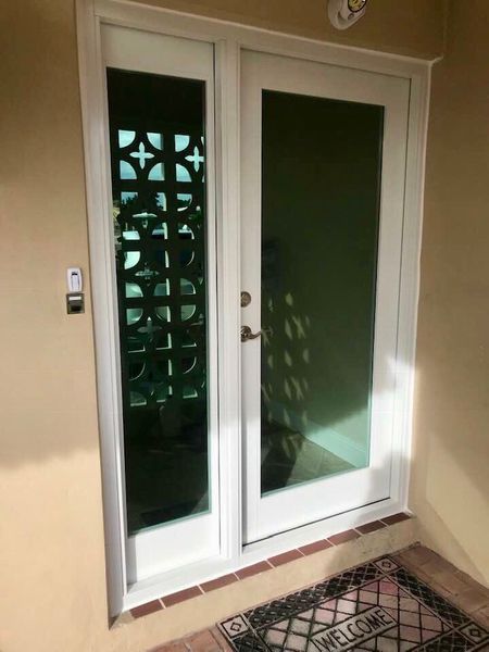 White double doors with glass and decorative panel, leading to an interior. 