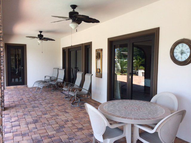 Covered patio with brick flooring, seating areas, and a clock on the wall.
