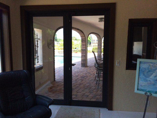 Glass double doors open to a patio with a swimming pool. A leather chair sits nearby.