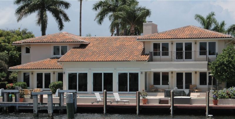 Waterfront house with a clay tile roof and a dock.