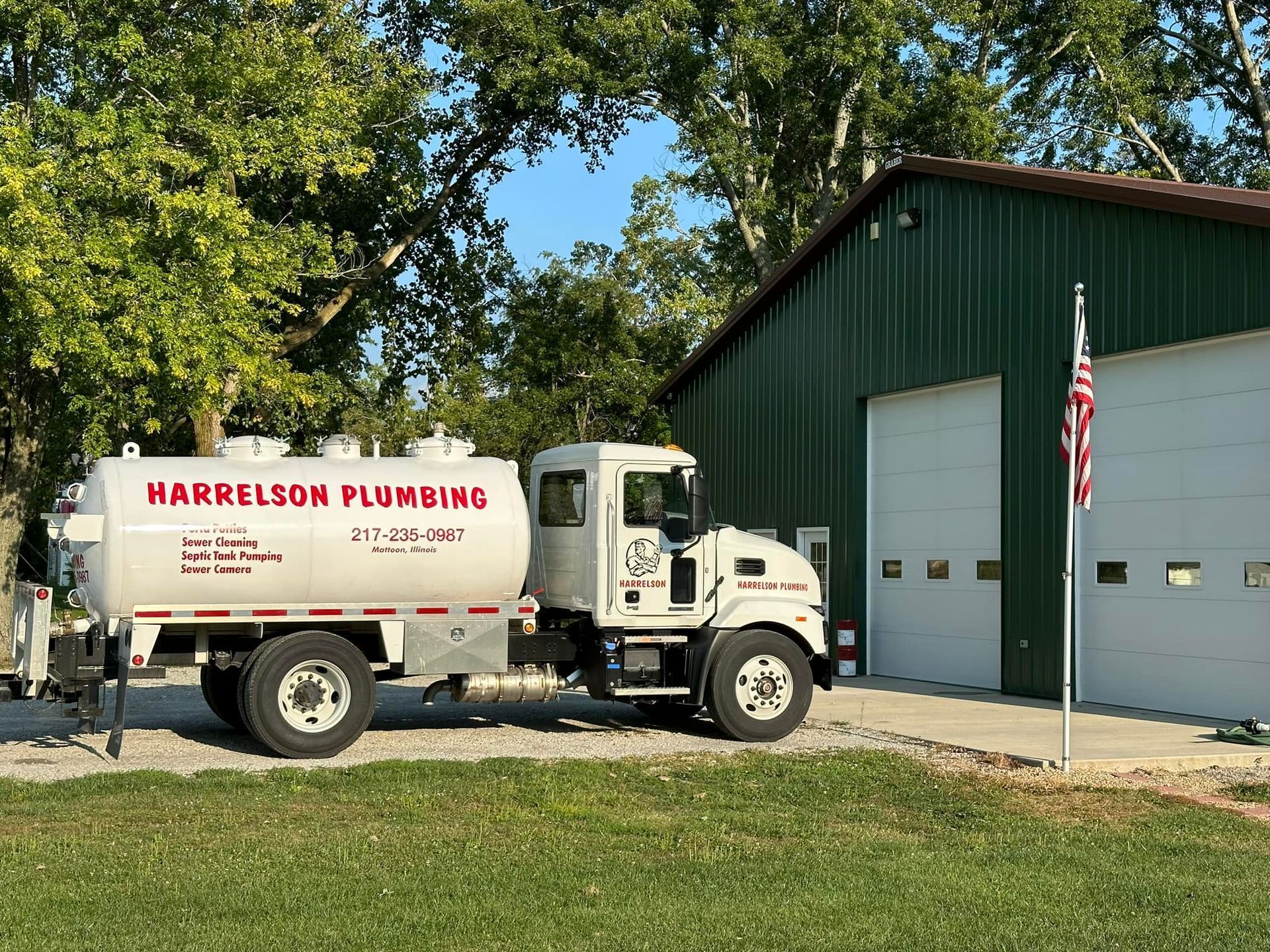 Harrelson Plumbing truck parked in front of a green building with garage doors.