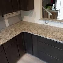 A kitchen with granite counter tops and gray cabinets.