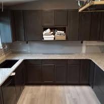 A kitchen with black cabinets and granite counter tops.