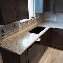 A kitchen with granite counter tops and black cabinets.