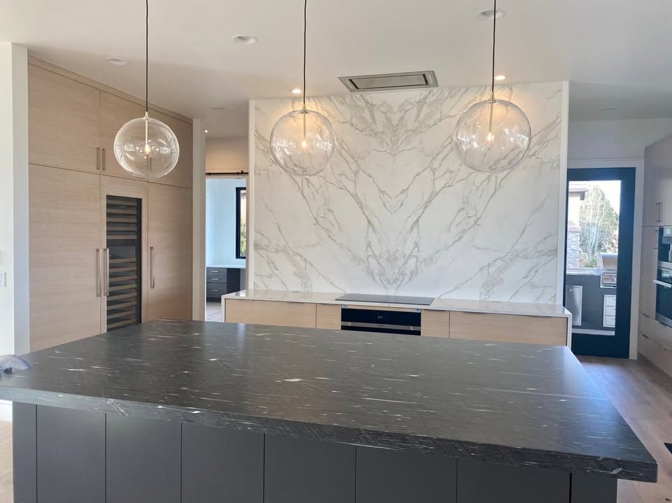 A kitchen with a large island and a marble wall
