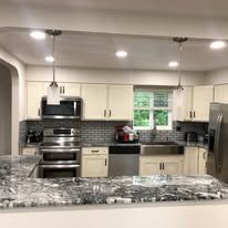 A kitchen with stainless steel appliances , granite counter tops , and white cabinets.