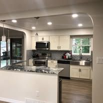 A kitchen with white cabinets , stainless steel appliances , a sink and a window.