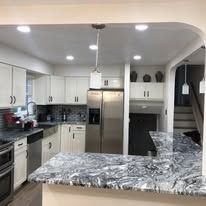 A kitchen with stainless steel appliances , granite counter tops , and white cabinets.