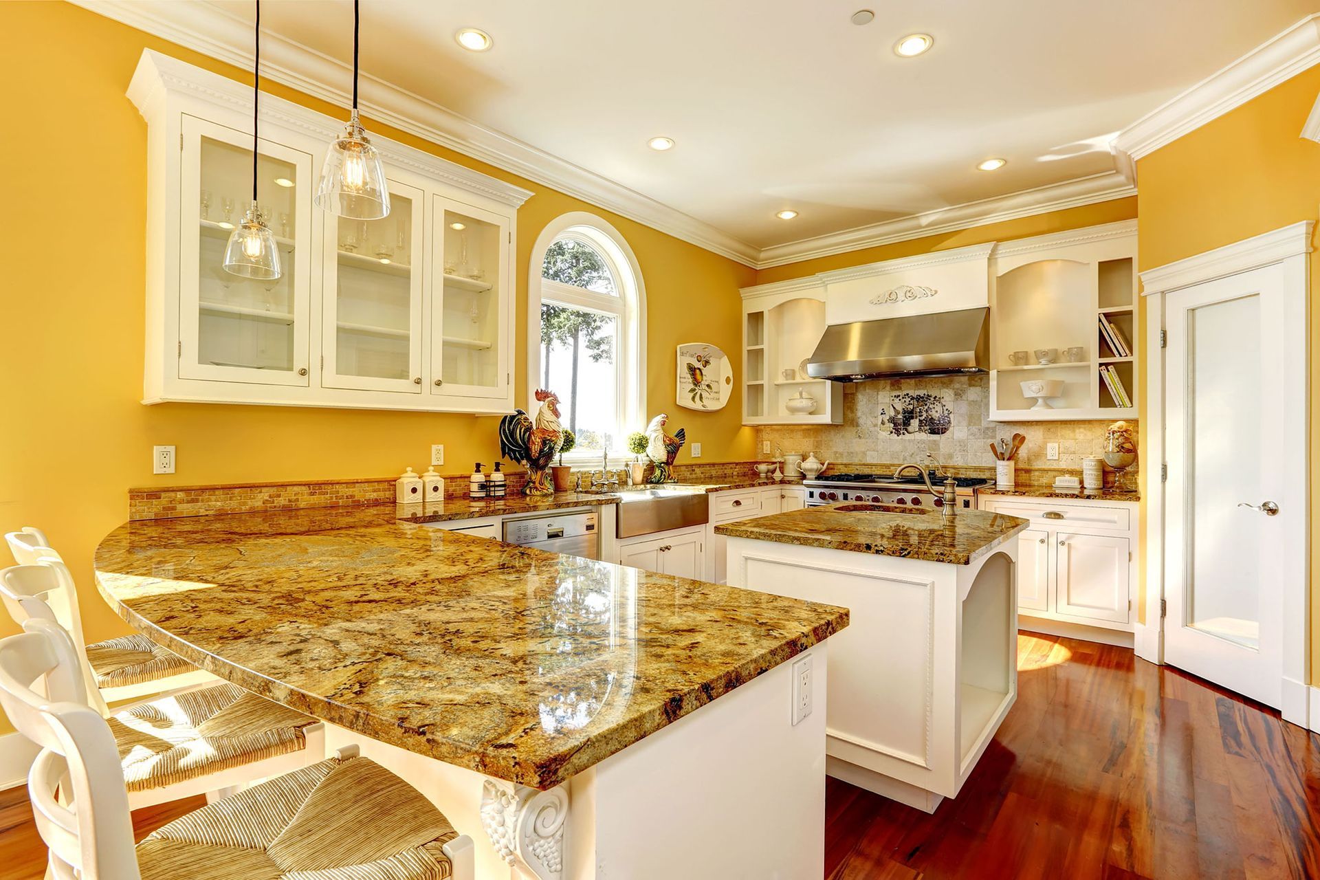 A kitchen with yellow walls, granite countertops, white cabinets, and stainless steel appliances.