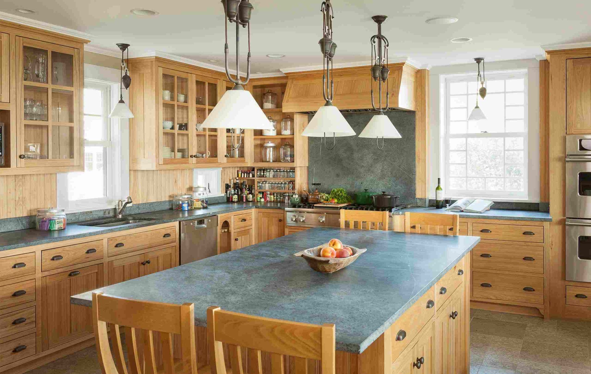 A kitchen with a large island and a bowl of fruit on it