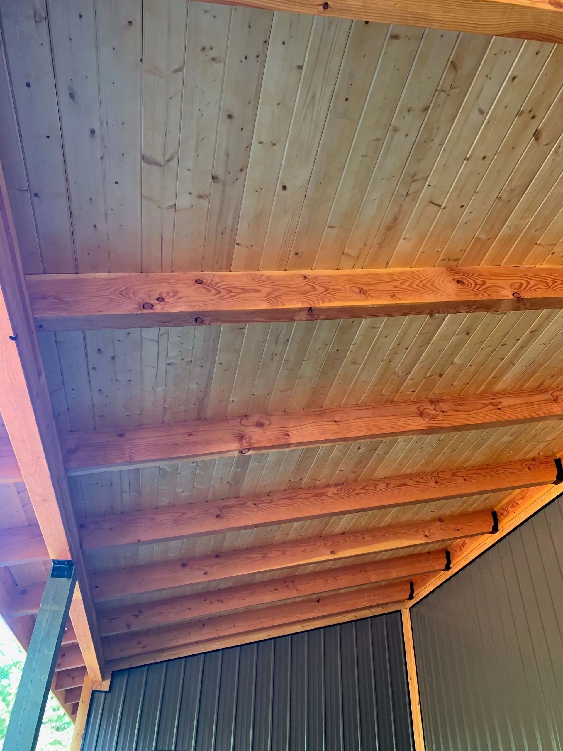 Wooden ceiling with brown beams and vertical wood paneling.